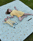 Girl and baby relaxing on Boho Picnic Rug Plus during outdoor family time