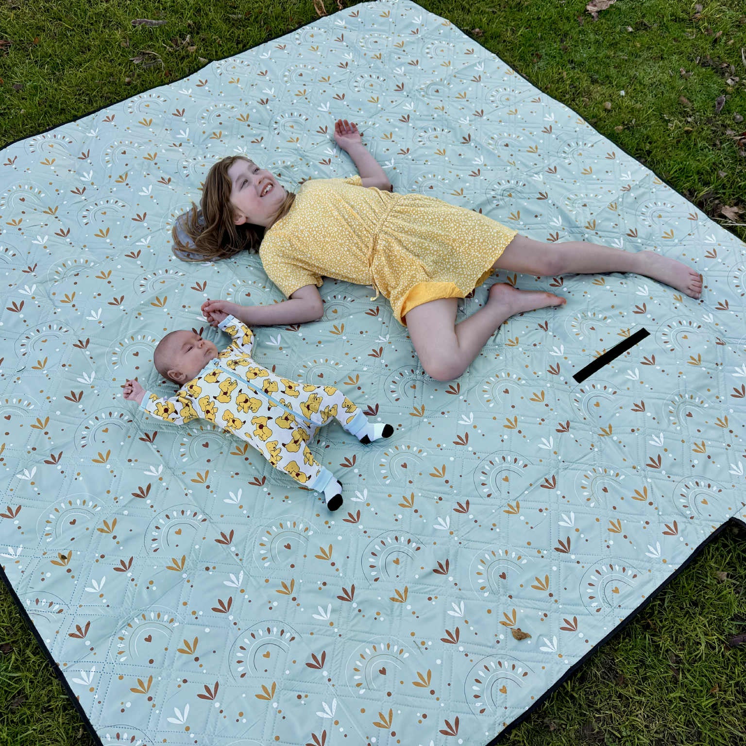 Girl and baby relaxing on Boho Picnic Rug Plus during outdoor family time